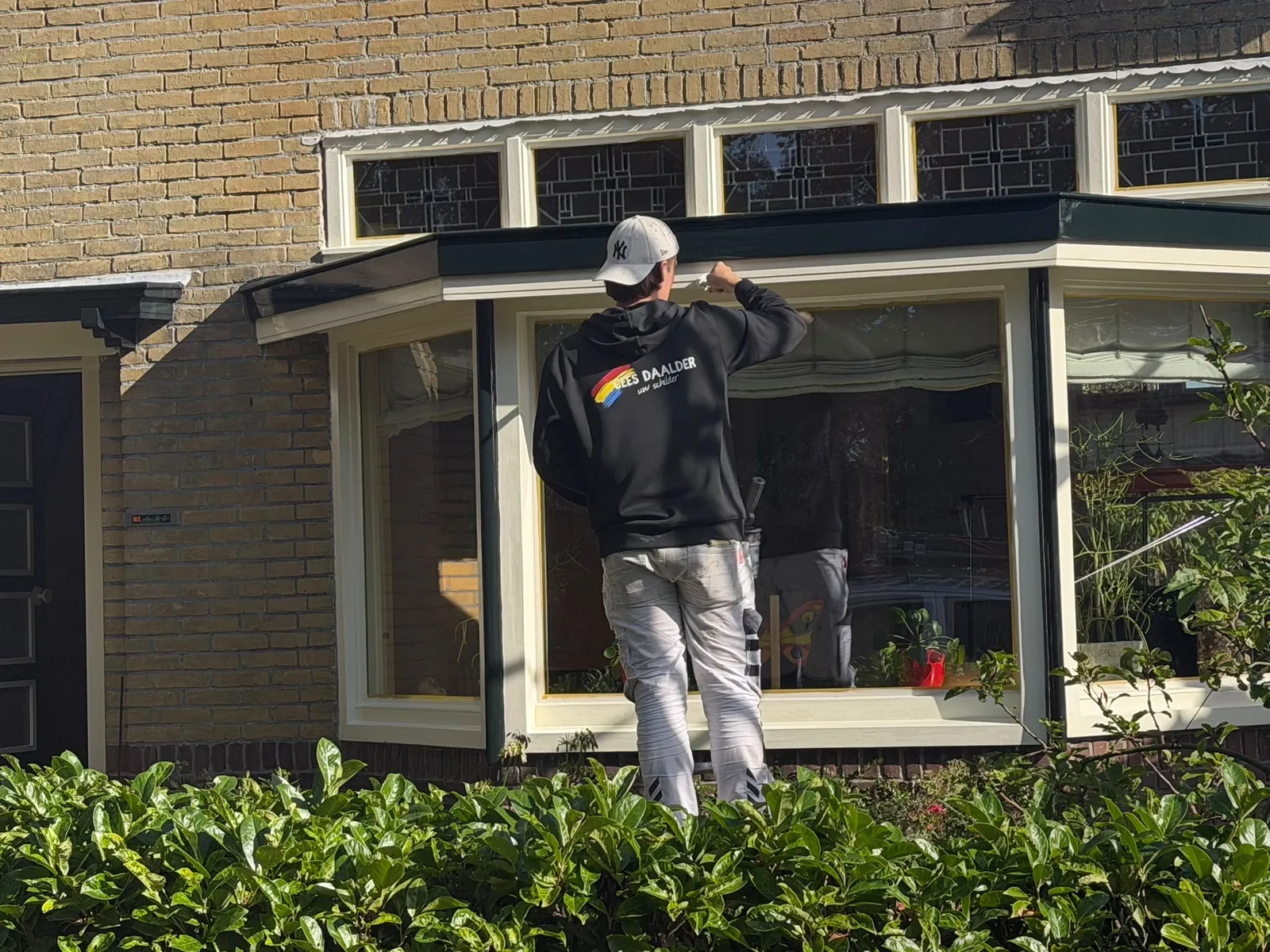 Schilder werkt aan de kozijnen van een erker