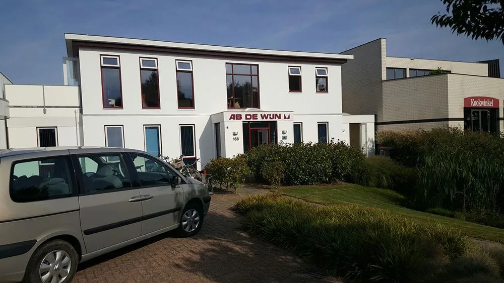 Bedrijfspand met geschilderde kozijnen, gezien vanaf de parkeerplaats